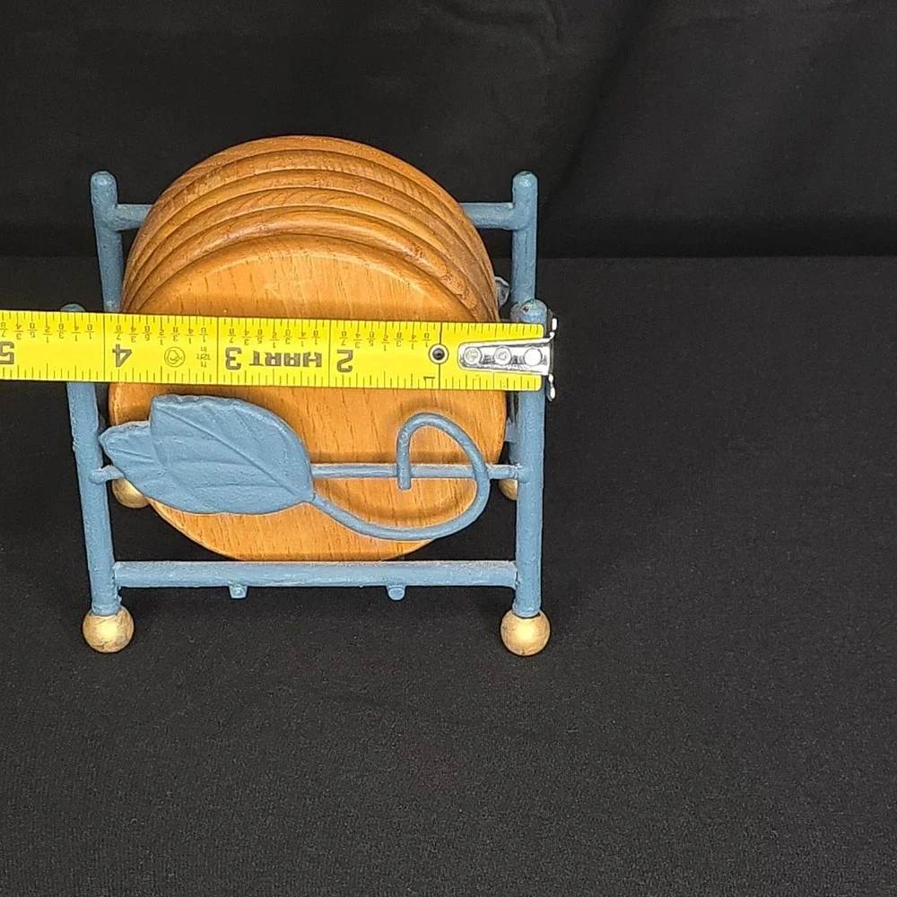 a vintage wooden drink coasters in a blue metal holder with leaf-shaped accents